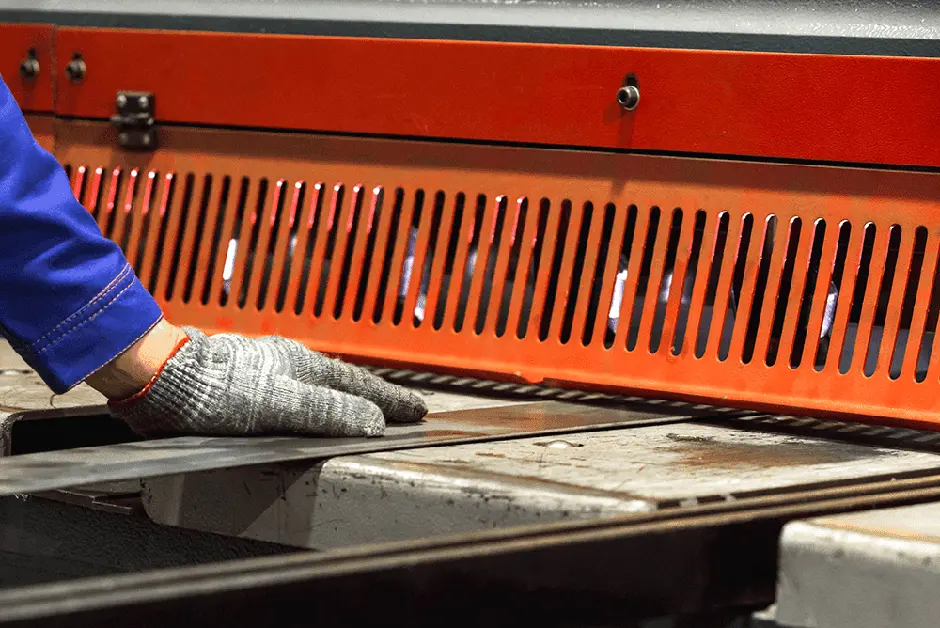 A person wearing gloves is working on a piece of metal