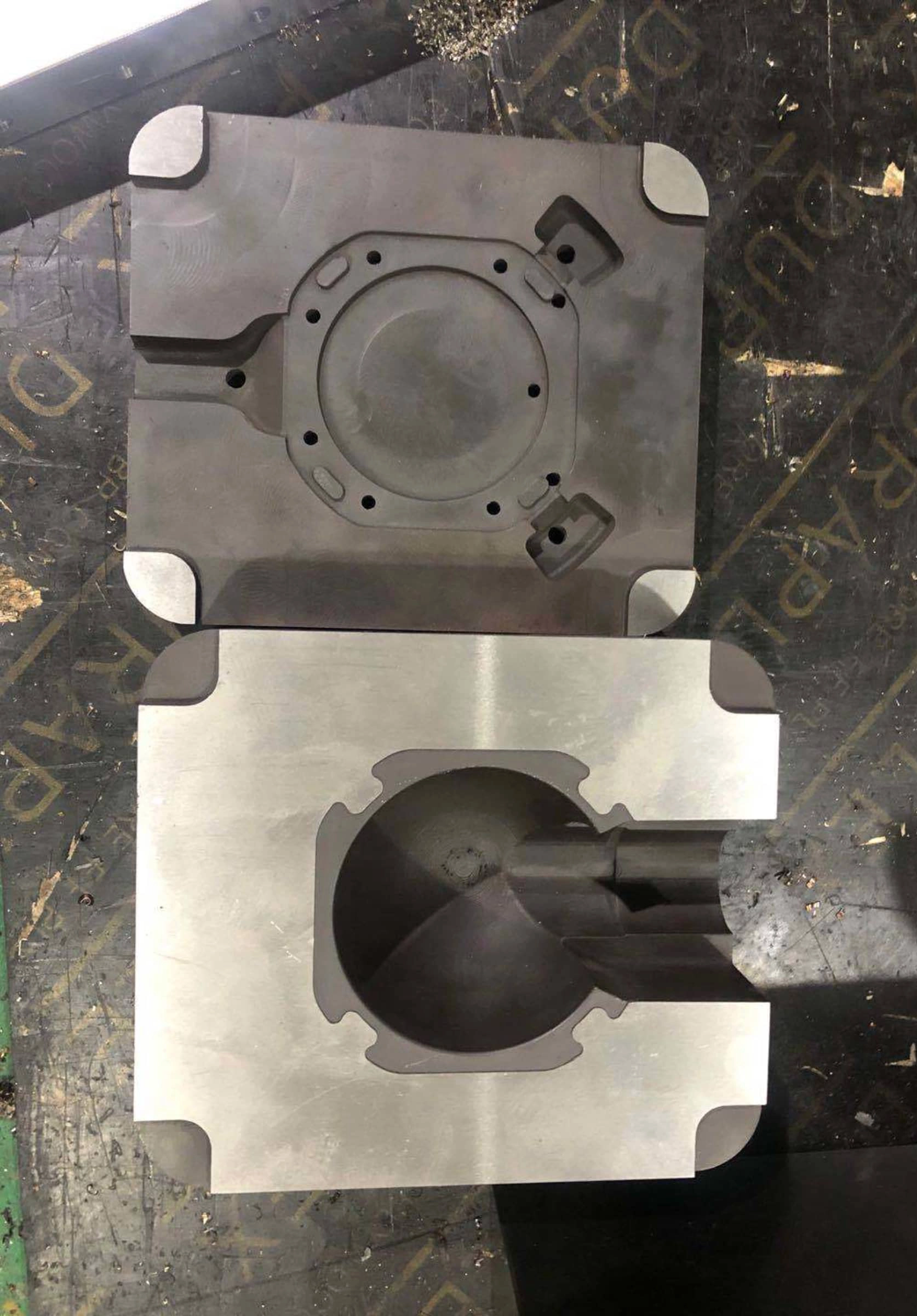 Metal industrial mold with circular cutout on textured workshop surface
