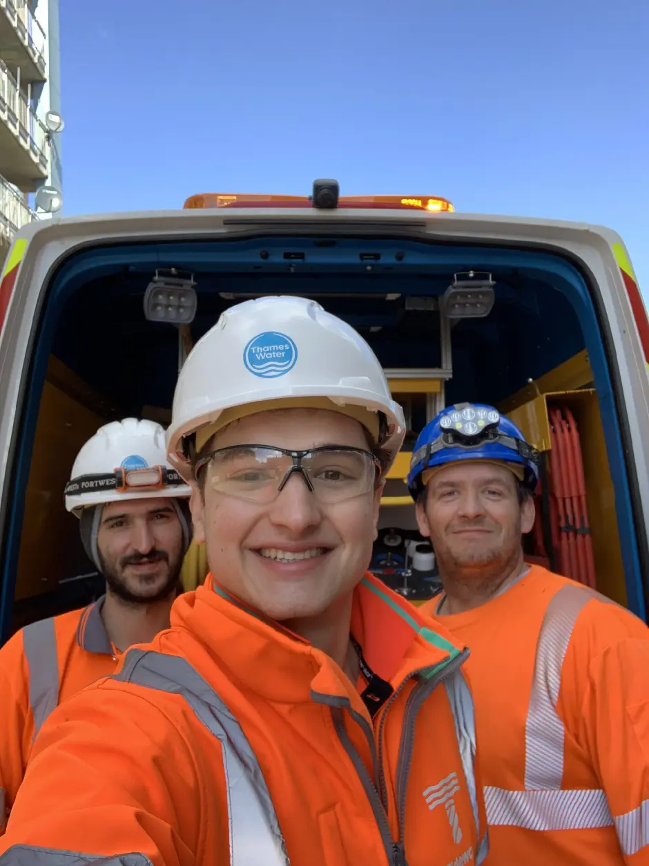 Three Thames Water workers in safety gear take a smiling selfie near van
