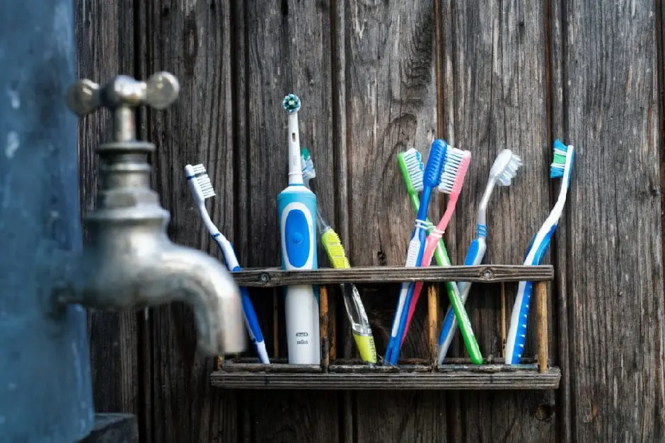 A wooden shelf holding a bunch of toothbrushes and a faucet