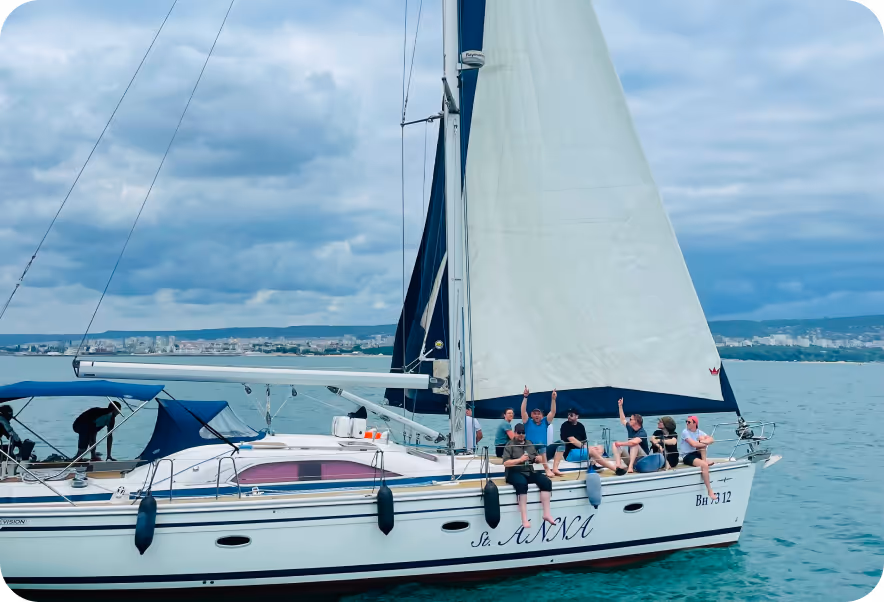 Digimondo team enjoying a sailboat on the water, with a clear sky above and sails raised.