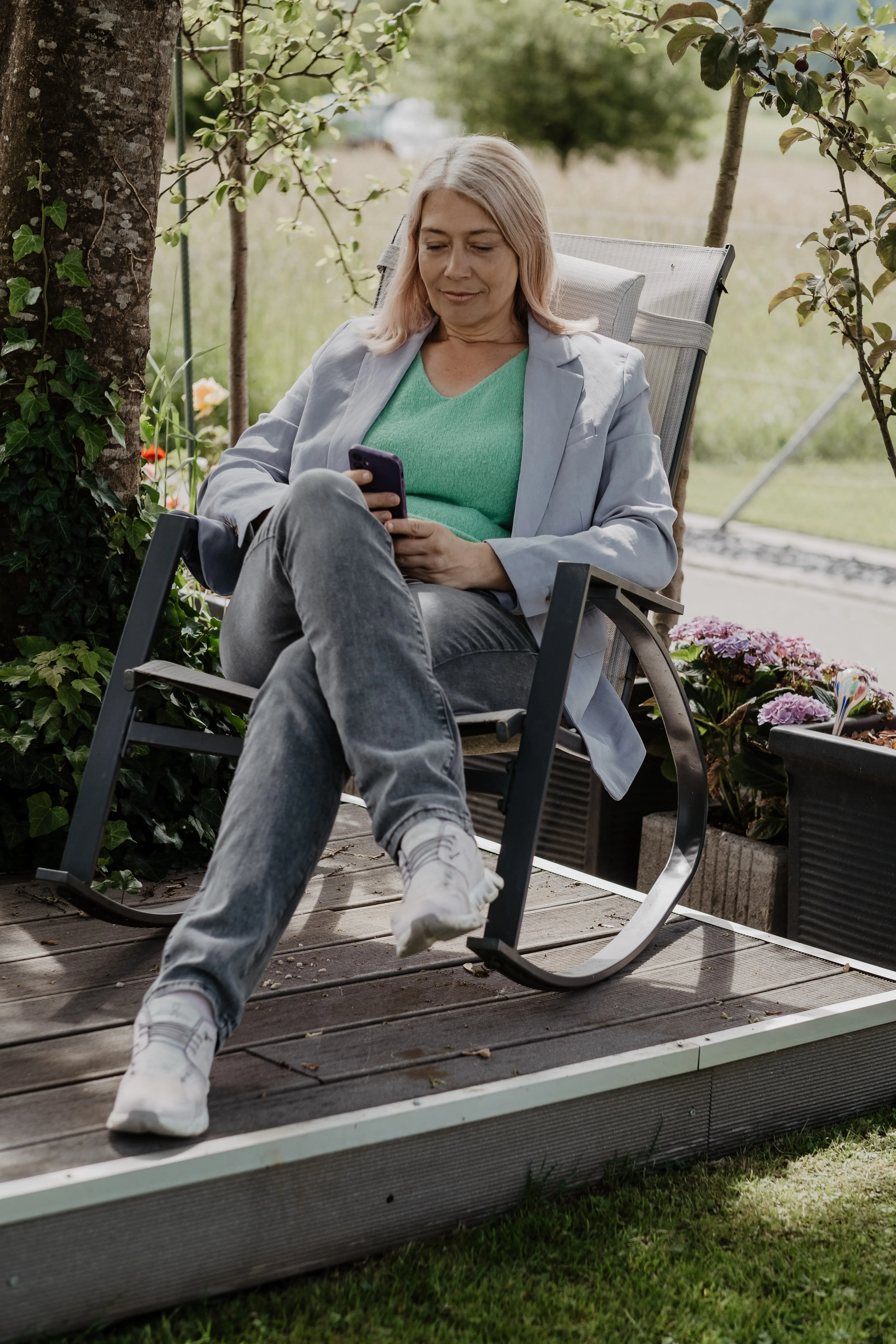 Judith Fiedler in einem Schaukelstuhl mit dem Smartphone in der Hand.