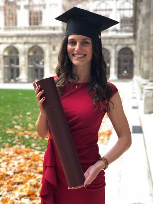 Isabella with her degree in front of the University