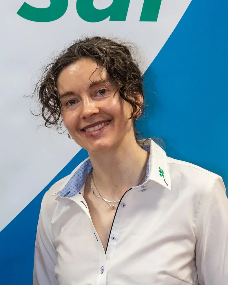 Seks kolleger foran sjøen med et produksjonsanlegg bak