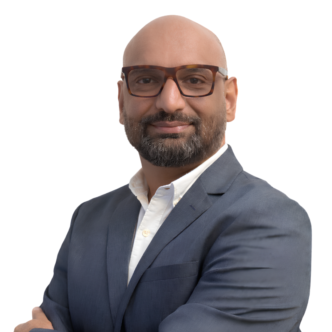 Man with a beard and glasses wearing a navy suit and white shirt smiling with crossed arms.