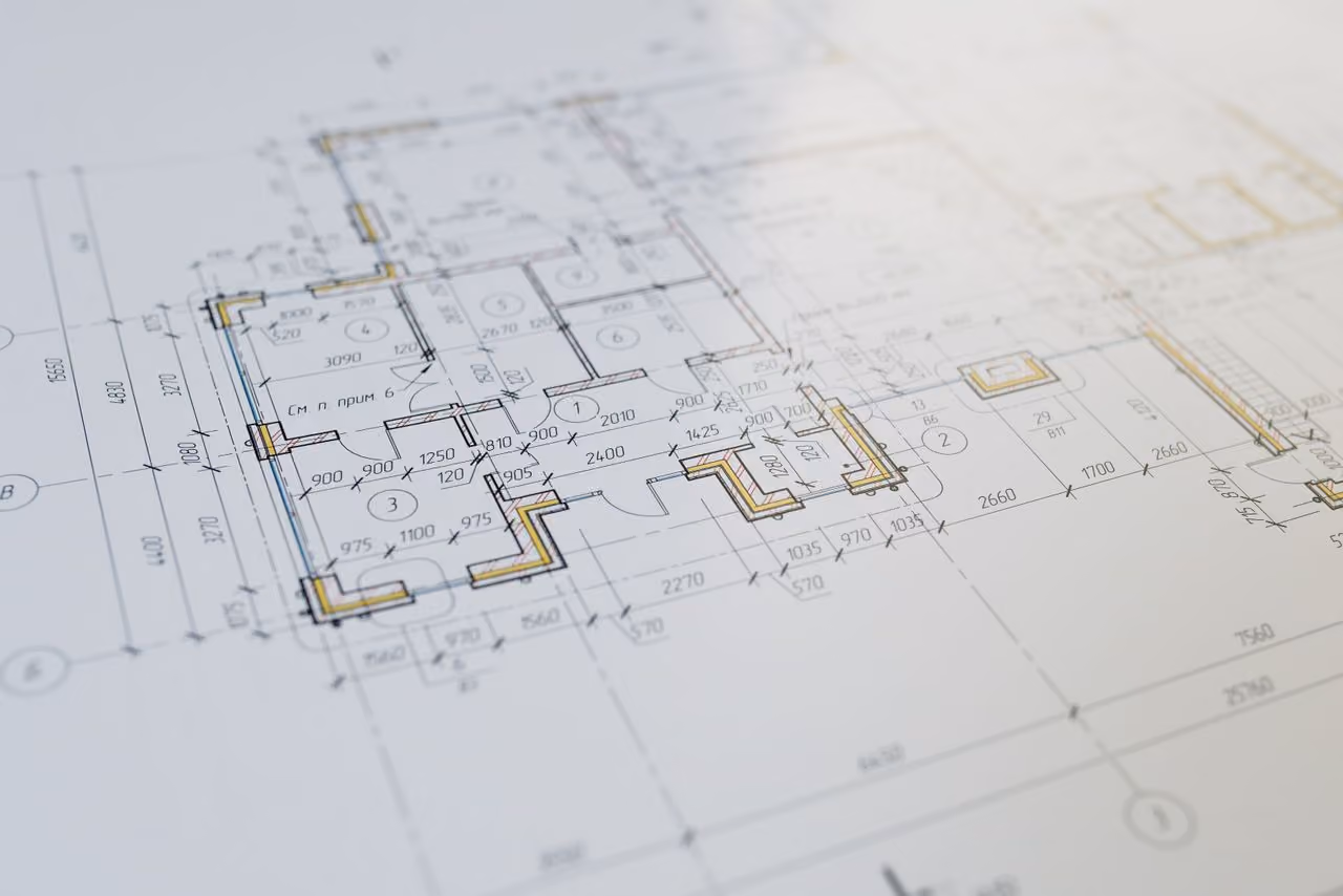 Architectural blueprint showing a detailed floor plan with room layouts, measurements, and construction annotations in black and yellow lines on white paper.