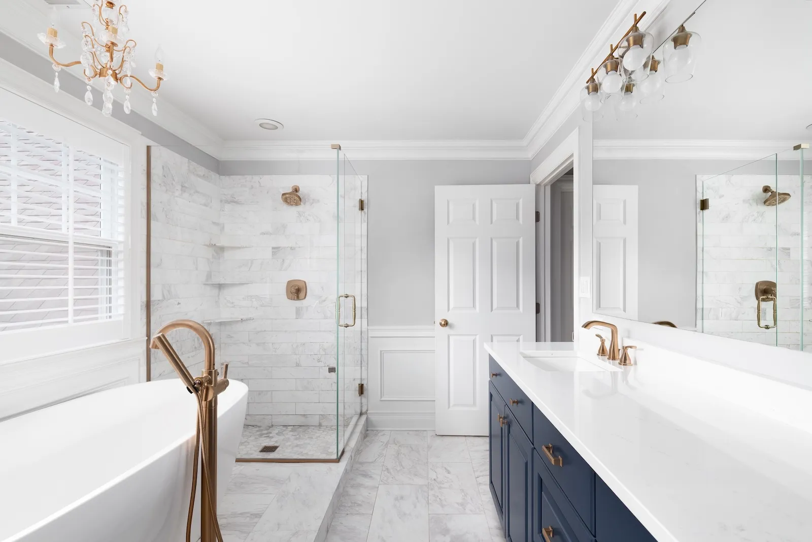 A beautiful luxury bathroom with bronze fixtures and whie tile and dark blue vanity