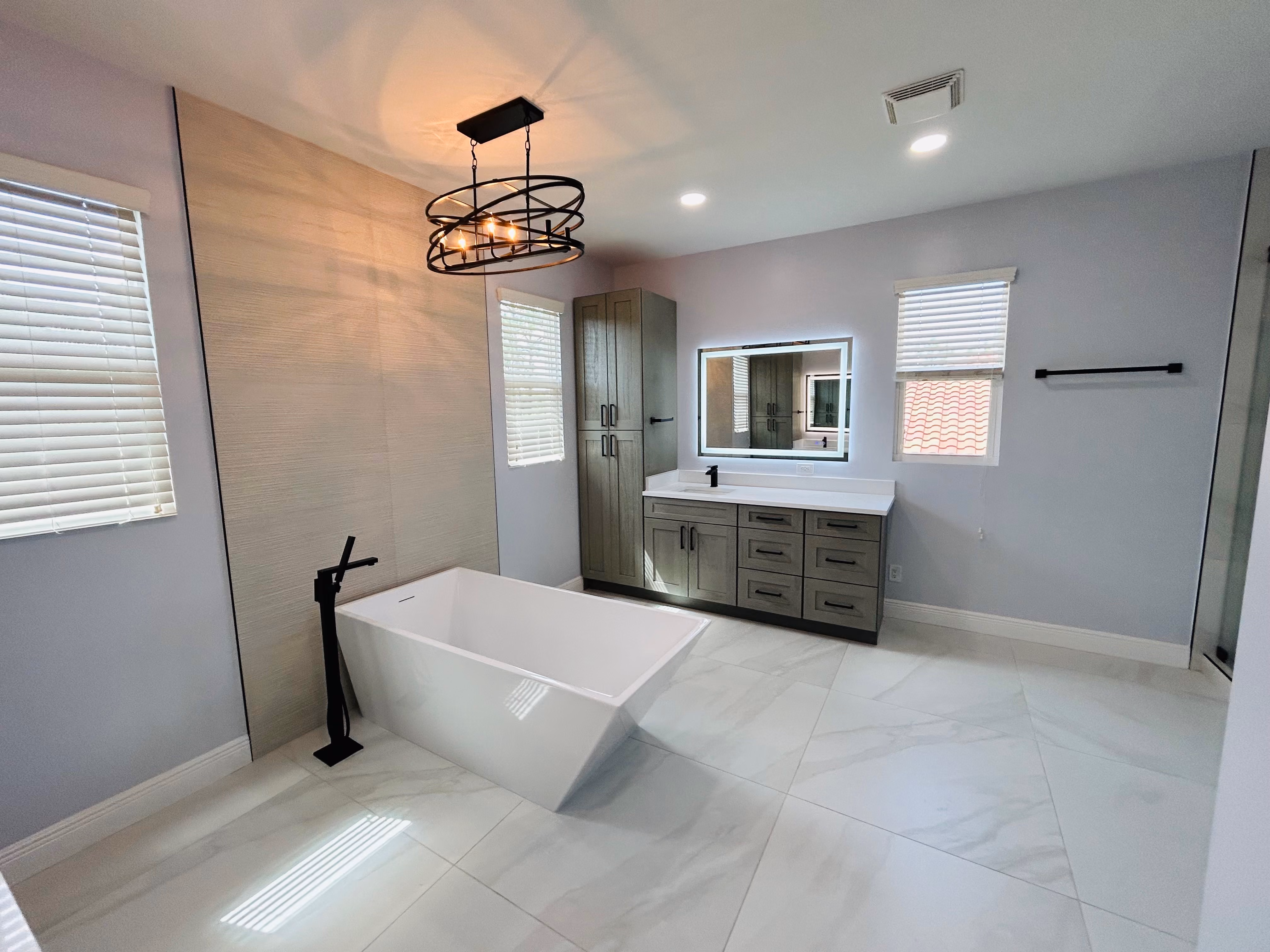Clean bathroom shower with sliding glass doors, silver fixtures, white tiles, toilet, and marble countertop.