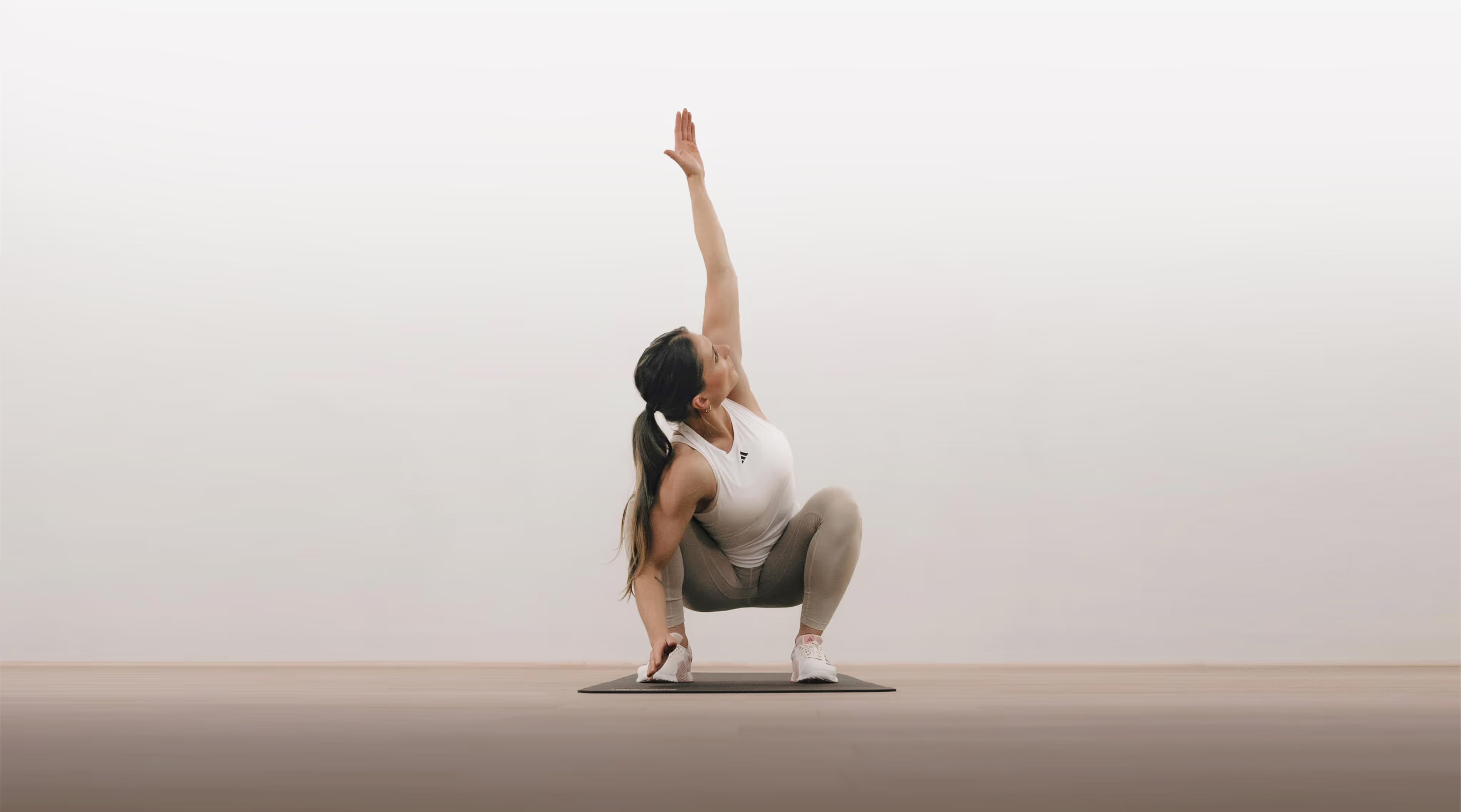 Woman performing GOWOD stretch in a light studio 