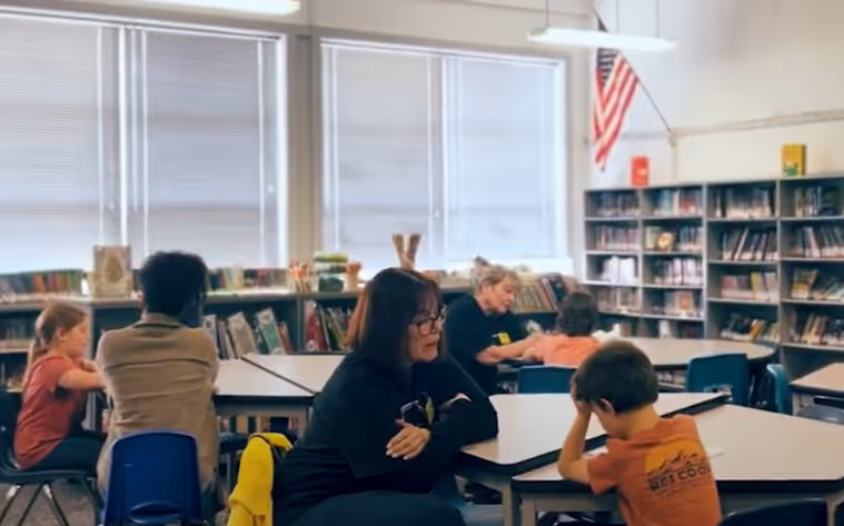A library setting with reading mentors reading with children. Be Undivided Lebanon is a wonderful example of a small town that is taking on literacy.