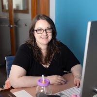 A women sitting at a desk and smiling at the camera. 