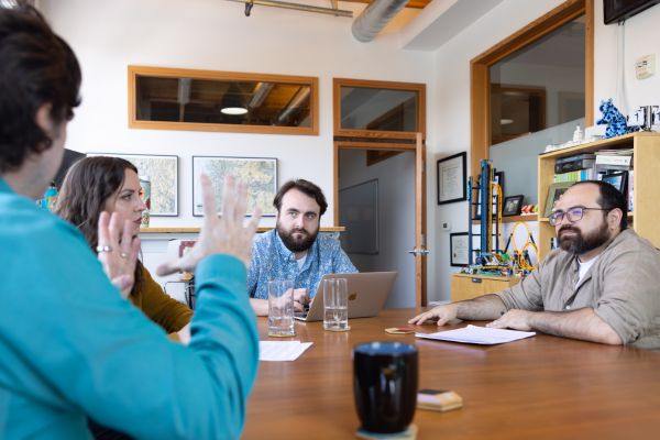 Three men and one women sitting at a conference table discussing business strategy. 