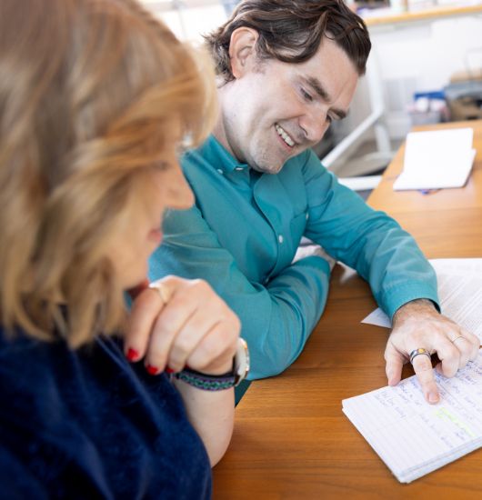 A man and a women sitting at a desk in an office. 
