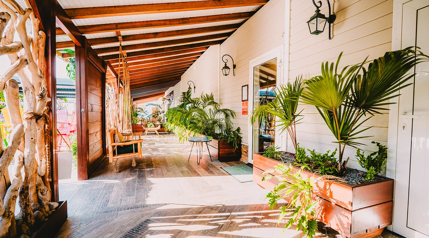Terrasse tropicale ombragée avec poutres bois palmiers et mobilier élégant Bambouresort Martinique