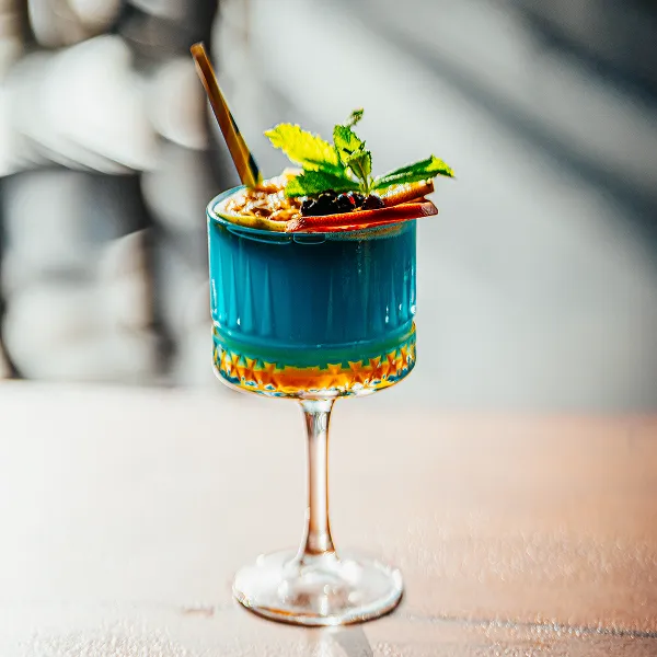 Tropical turquoise cocktail decorated with yellow flowers Bambouresort Martinique bar