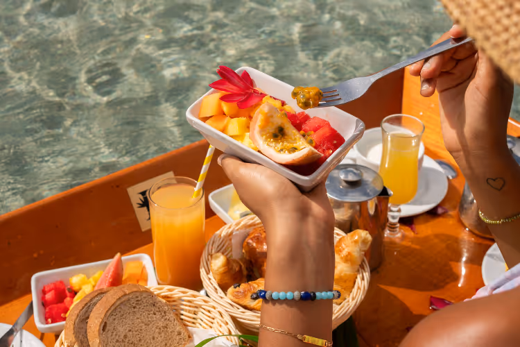 Petit déjeuner tropical avec fruits frais, pain, viennoiseries et jus d'orange en bord de mer