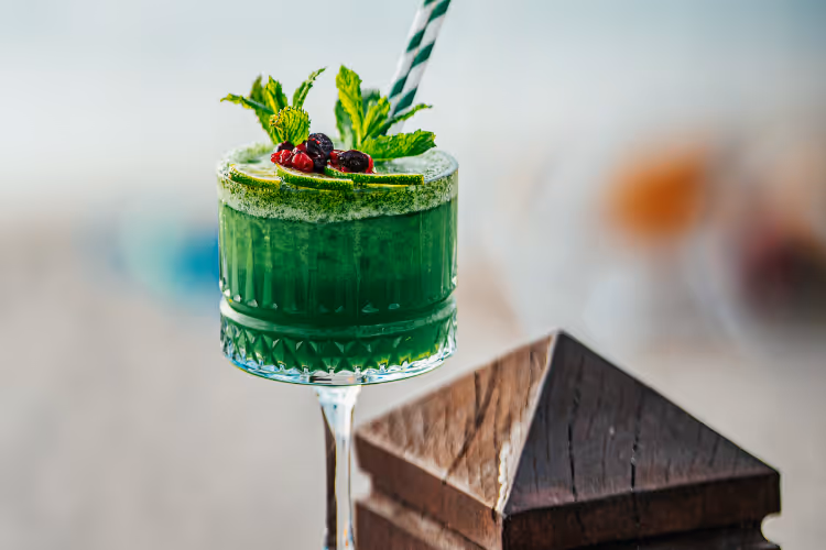 Cocktail vert menthe garni de fruits rouges dans verre cristal taillé