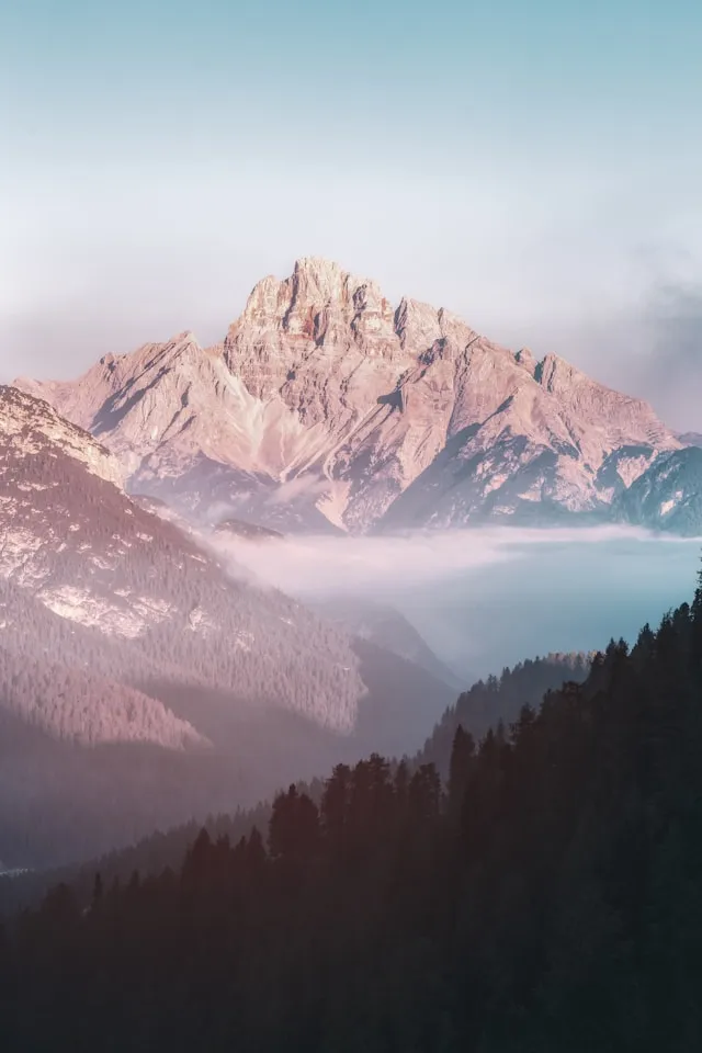 Rocky mountain peak emerging from morning mist Austrian Alps