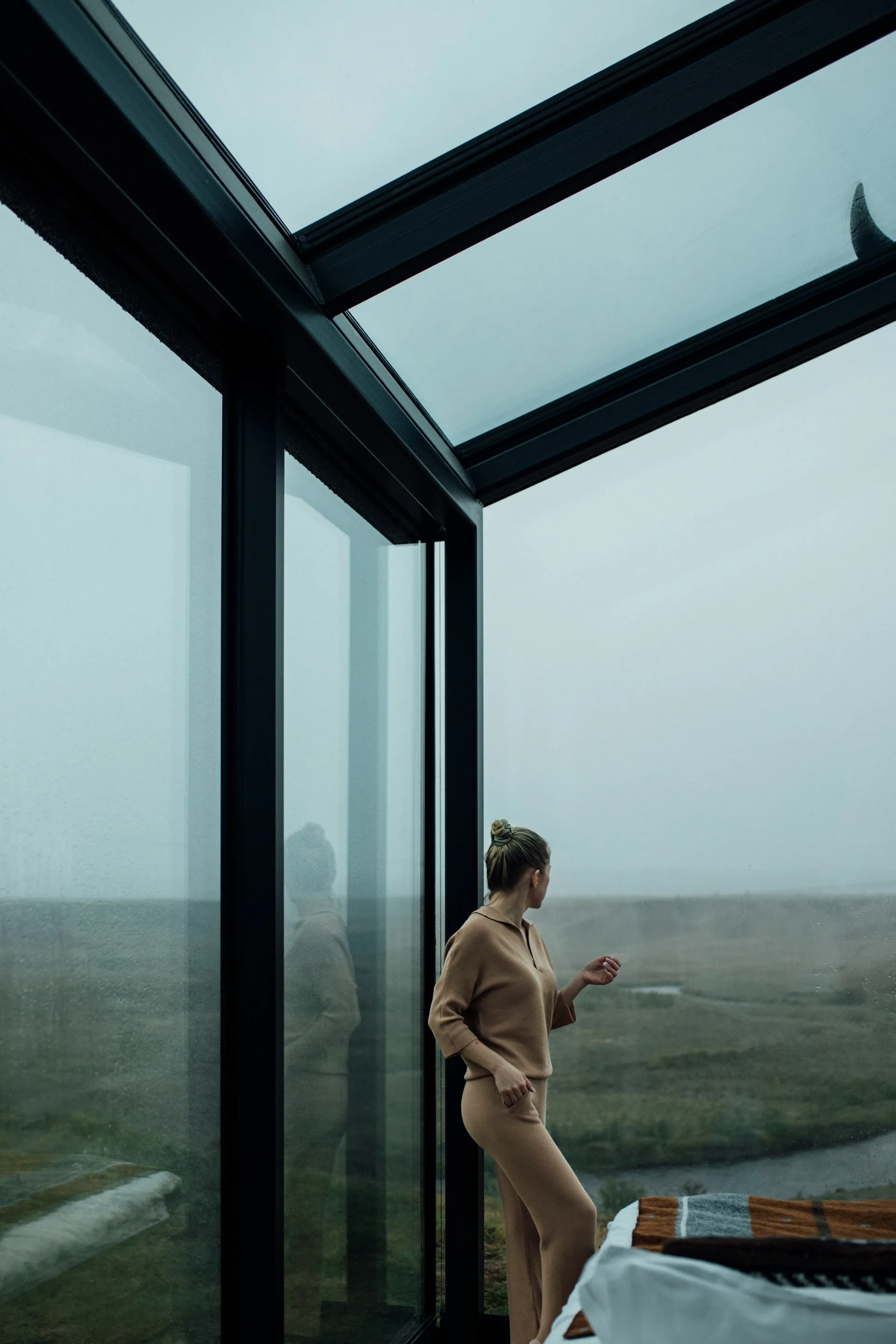 Silhouette contemplant le paysage brumeux depuis une chambre panoramique moderne
