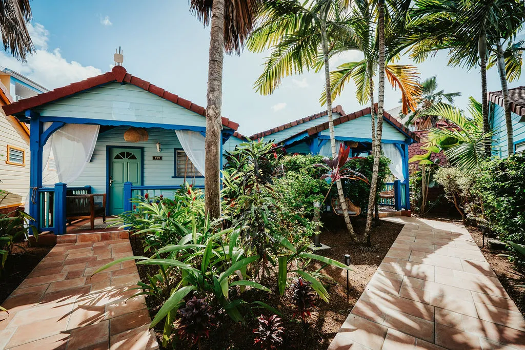 Bungalows bleu et blanc bordés de palmiers et plantes tropicales dans jardin exotique