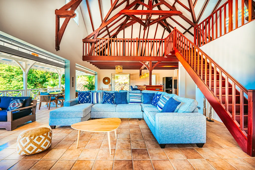 Spacious living room villa Bambouresort mezzanine red wood blue sofa tropical garden view Martinique