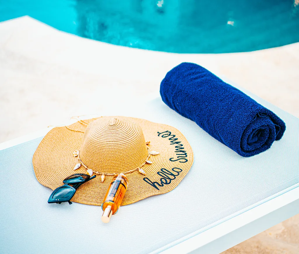 Straw hat Dolce Vitta sunglasses blue towel poolside luxury Martinique