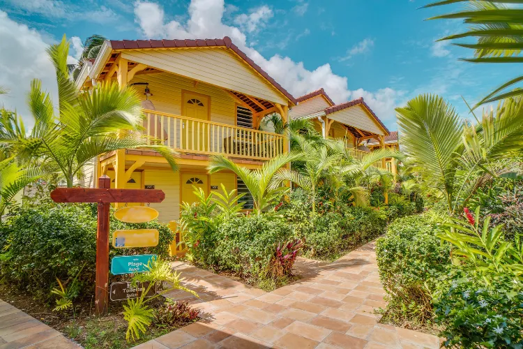 Luxurious yellow bungalows surrounded by palm trees and tropical vegetation Martinique Bambouresort