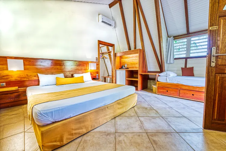 Luxury bungalow suite with king-size bed, exposed beams and relaxing bench Bambou Resort Martinique