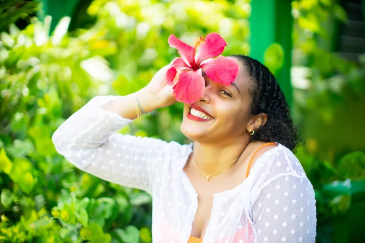 Woman holding red hibiscus flower in tropical garden Bambouresort Martinique