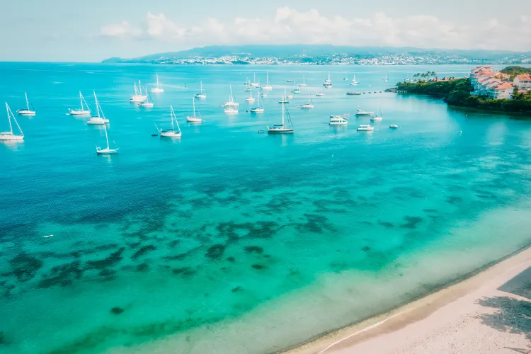 Sailboats anchored in turquoise Martinique bay aerial view of BambouResort beach