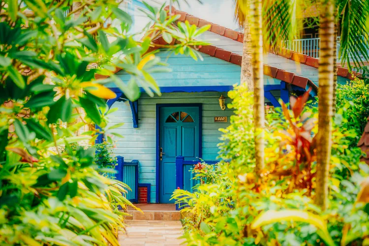 Tropical bungalow with blue door surrounded by palm trees and lush vegetation Bambouresort Martinique