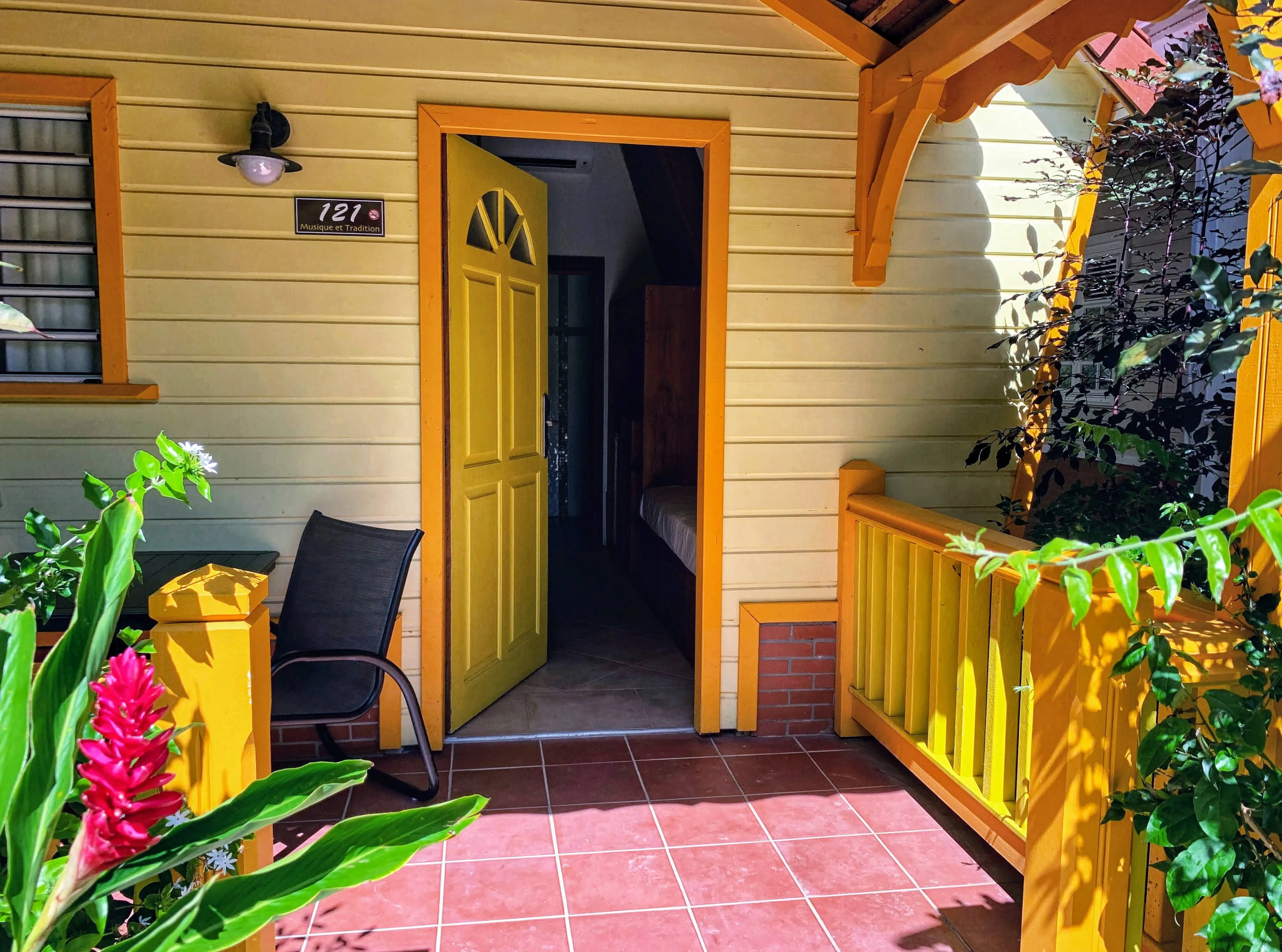 Tropical yellow bungalow with green front door and flower-filled terrace Bambouresort Martinique