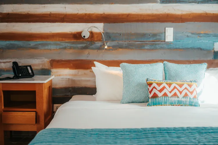 King size bed with turquoise cushions in luxury bungalow with wooden walls Bambou Resort Martinique