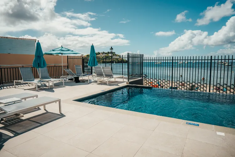 Infinity pool with sea view and white deckchairs BambouResort Martinique