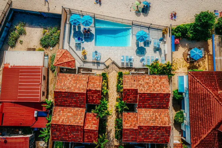 Luxury bungalows with red roofs bordering a turquoise pool with aerial view Bambou Resort Martinique