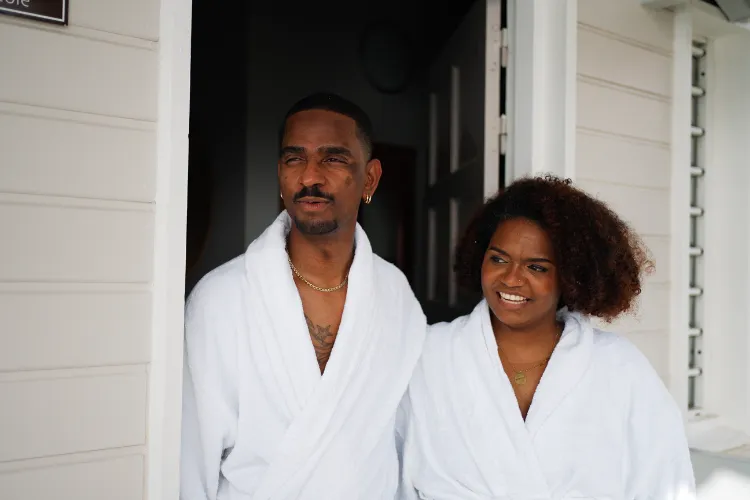Couple in white bathrobes relaxing in front of luxury bungalow Bambou Resort Martinique