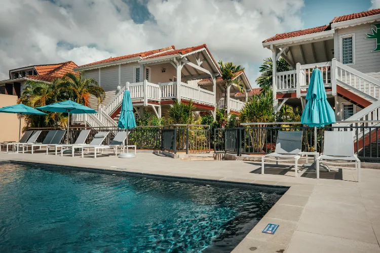 White bungalows terrace pool view resort Martinique turquoise parasols deckchairs palm trees