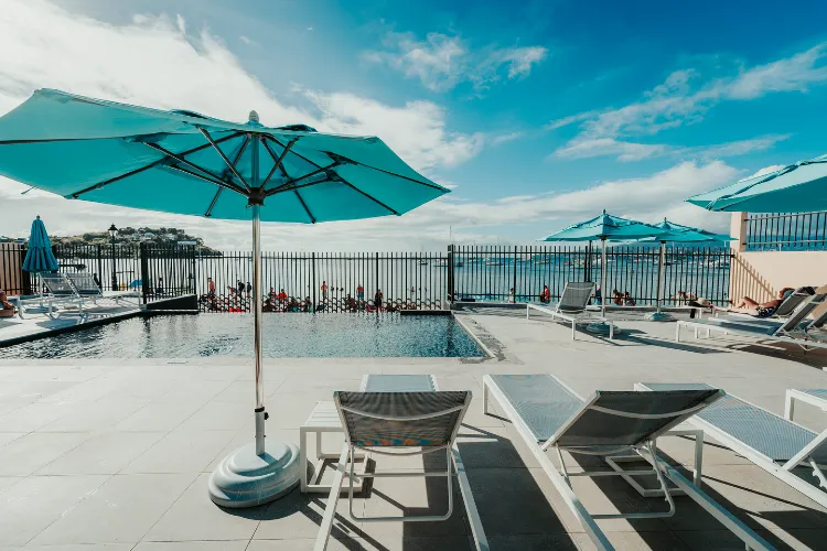 Piscine à débordement et transats sous parasols turquoise vue mer Martinique Bambouresort