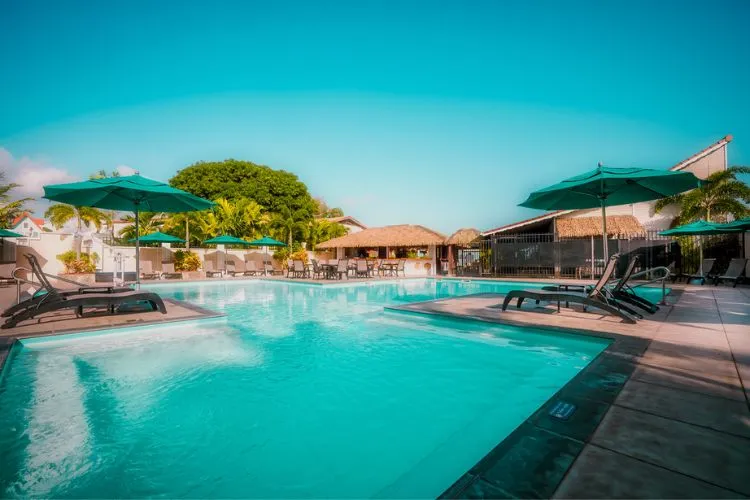 Luxury swimming pool lined with green parasols resort Bambou Martinique deckchairs relaxation