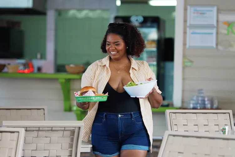 Waitress at Le Karayib restaurant carrying two Creole dishes to the Bambou Resort terrace in Martinique
