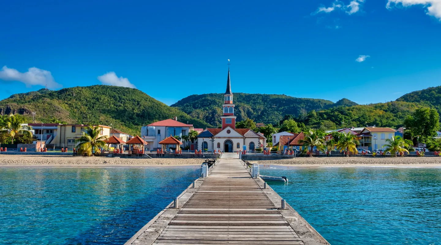 Pontoon wood church Anse d'Arlet beach Martinique palm trees mountain turquoise sea