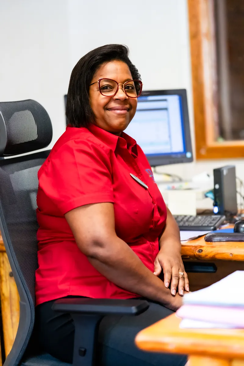 Welcoming professional in red shirt seated at BambouResort Martinique reception desk