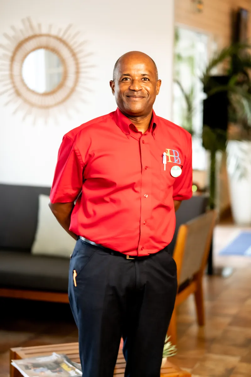 Professional in red shirt and blue pants welcoming guests in the lobby of Bambou Resort Martinique