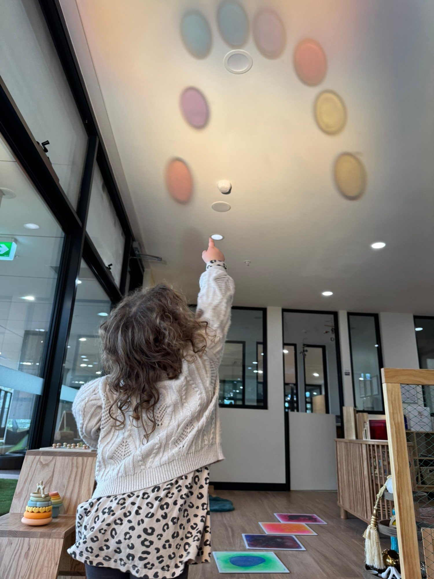 A child pointing up at coloured light circles on the classroom ceiling