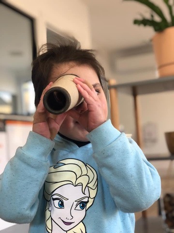 A child looking through a cardboard telescope