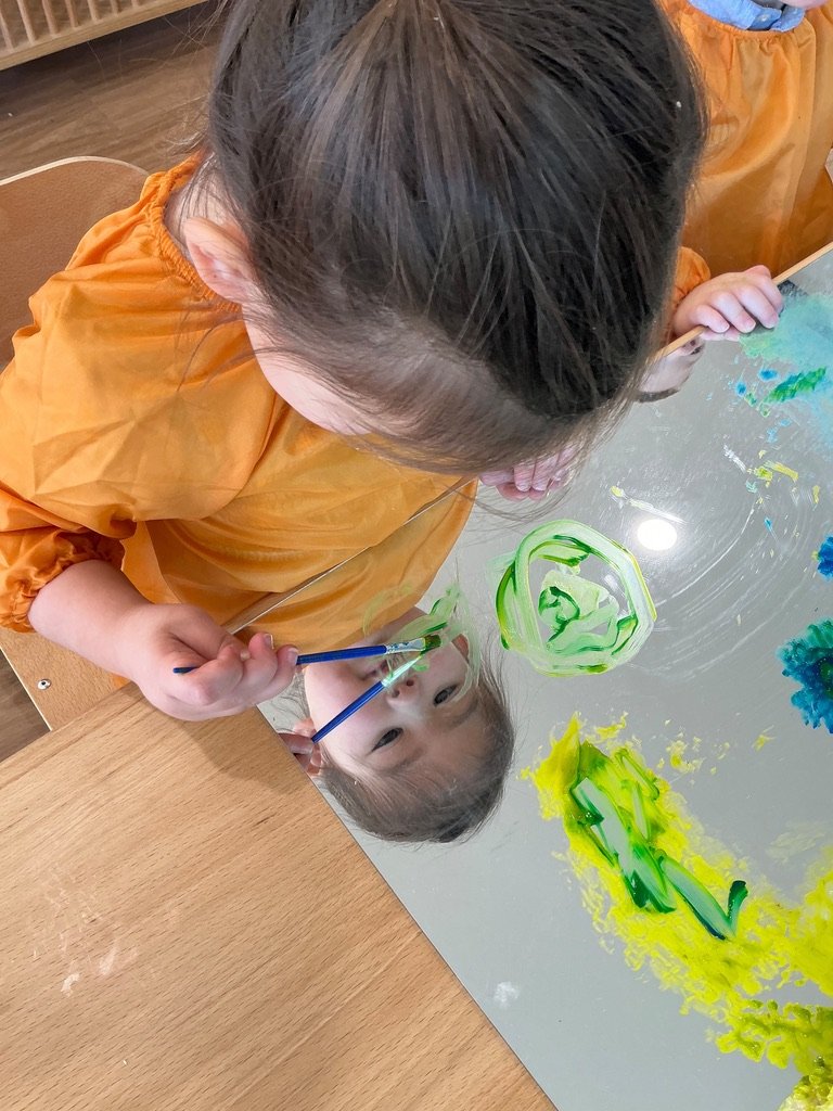 A child painting on a mirror