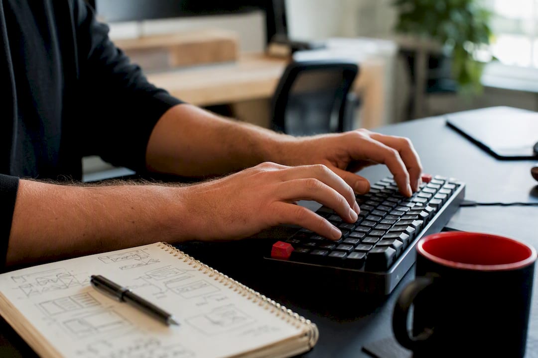 Hands typing near keyword research notes