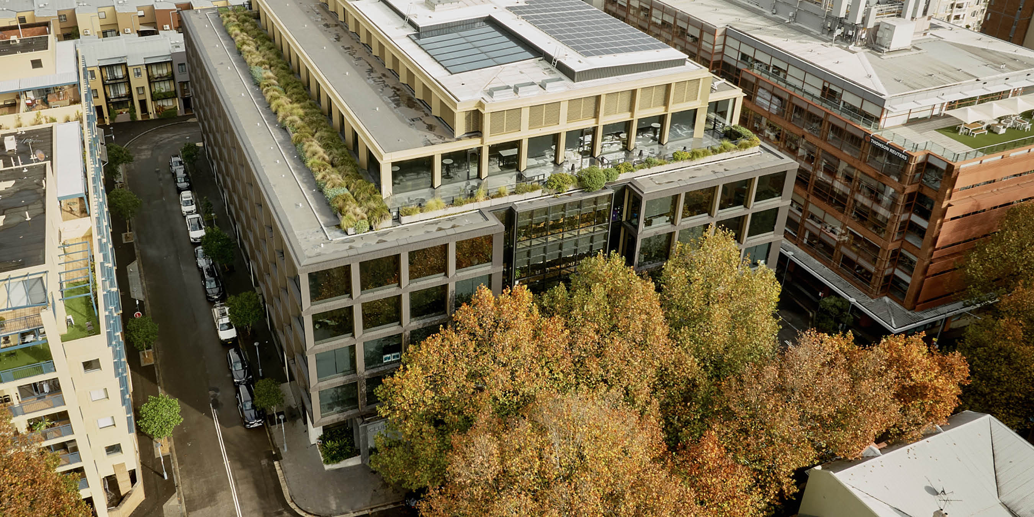 Exterior view of Surry Hills House Australia, modern office and dining space with large windows and vibrant street scene at dusk.