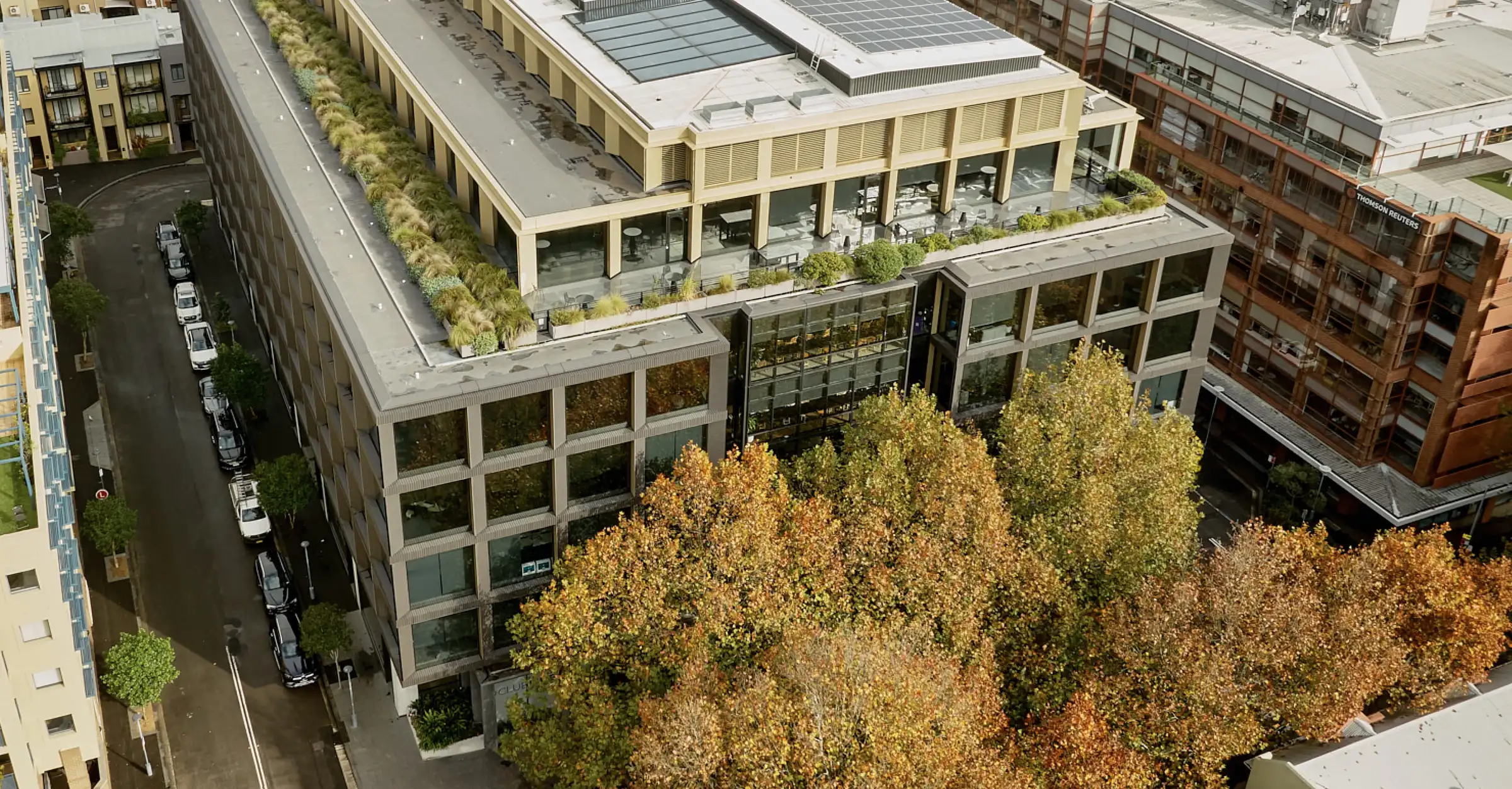 Exterior view of Surry Hills House Australia, modern office and dining space with large windows and vibrant street scene at dusk.