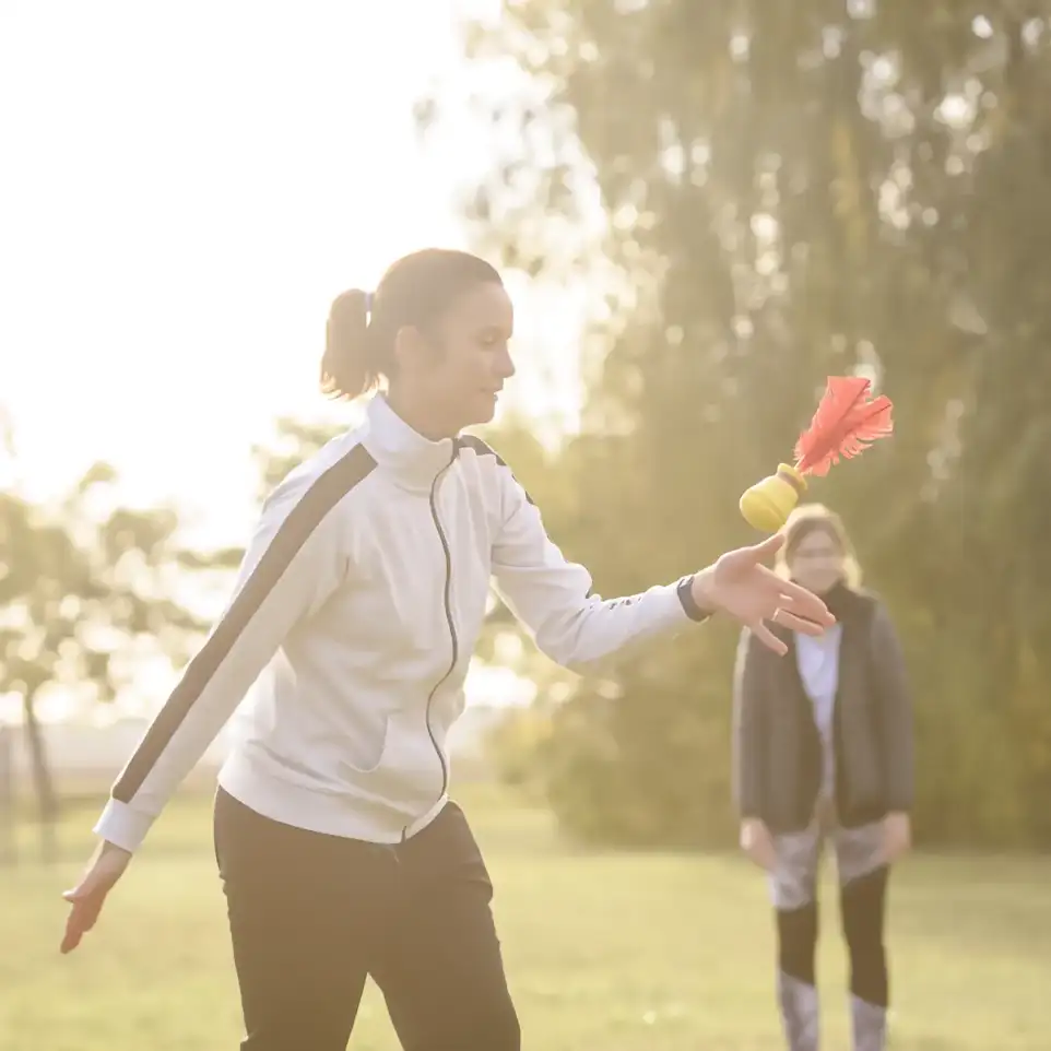 Eine Frau fängt einen gefiederten Ball, der ihr zugeworfen wurde.